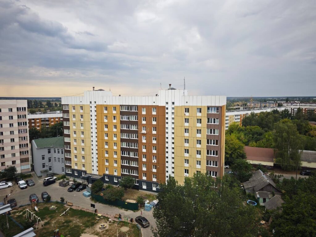 Будівельники ремонтують під'їзд багатоповерхового житлового будинку, укладають плитку в коридорі