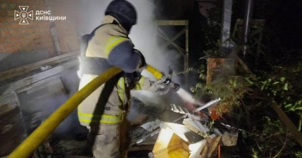 Пожежники гасять вогонь на тлі пошкодженого багатоповерхового будинку вночі