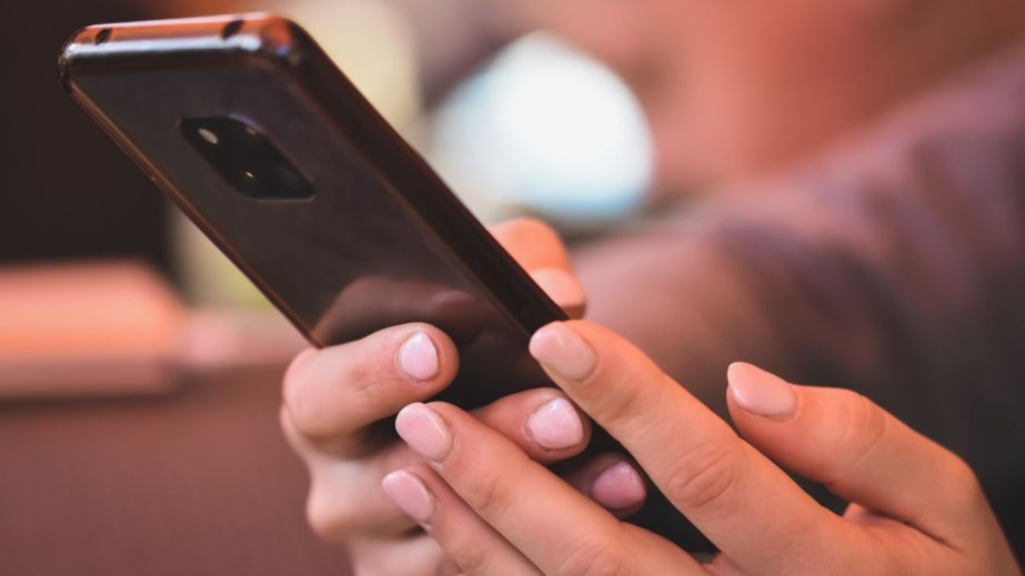 Смартфон із вхідним SMS на тлі будівлі міської ради